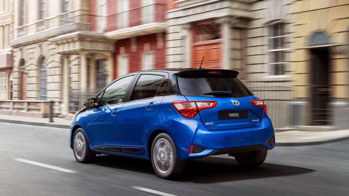 Toyota-Yaris-Hybrid-driekwart-achteraanzicht-rijdend-stad